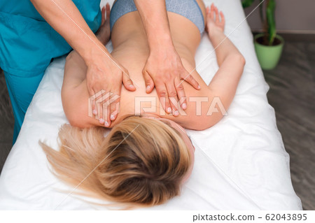 Hands of a massage therapist doing back massage of 62043895