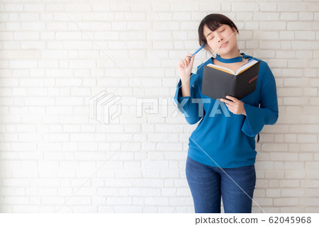 Beautiful asian woman smiling standing thinking and writing notebook on concrete cement Beautiful asian woman smiling standing thinking and writing notebook on concrete cement 62045968