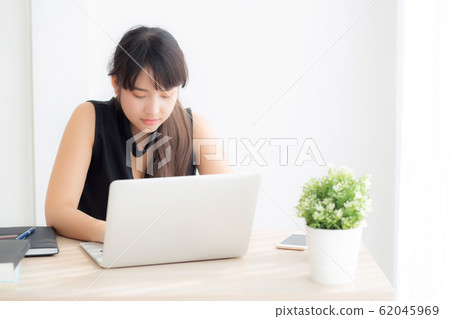 Beautiful young freelance asian woman smiling working and typing on laptop computer 62045969