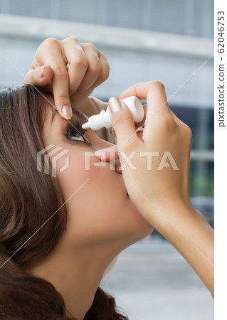 woman using eye drop, eye lubricant to treat dry woman using eye drop, eye lubricant to treat dry 62046753