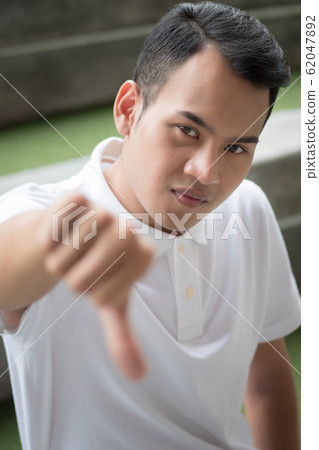 rejecting man showing thumb down gesture; man 62047892