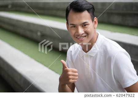 happy man giving thumb up gesture; smiling 62047922