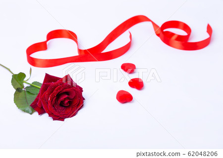 Red rose, ribbon and hearts on a white background. Valentine's Day, Birthday, Mother's Day, International Women's Day. Close-up, selective focus. Red rose, ribbon and hearts on a white background. Valentine's Day, Birthday, Mother's Day, International Women's Day. Close-up, selective focus. 62048206
