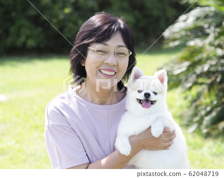 Smiling senior woman embracing dog Smiling senior woman embracing dog 62048719