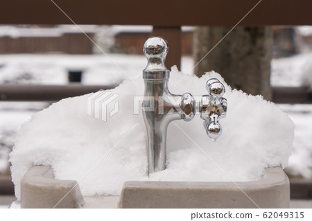 Frozen snow frozen faucet winter in public park. 62049315