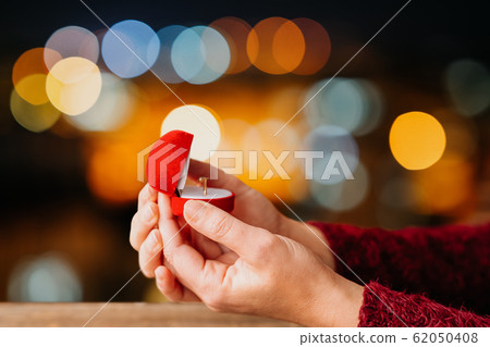 Woman open her gift box jewellery with bokeh led lights background. Valentines day and romance concept. Woman open her gift box jewellery with bokeh led lights background. Valentines day and romance concept. 62050408