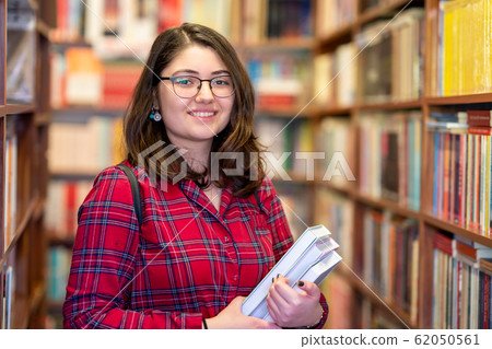 Intellectual Teenage girl choose books and pick them from a library or bookstore. Intellectual Teenage girl choose books and pick them from a library or bookstore. 62050561