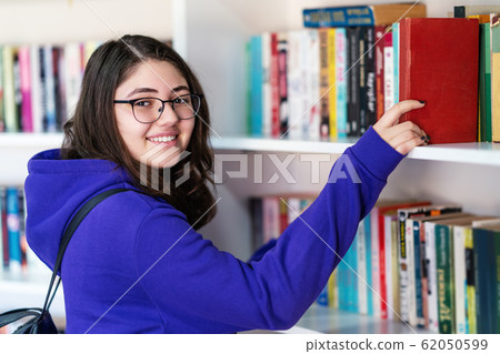 Intellectual Teenage girl choose books and pick them from a library or bookstore. Intellectual Teenage girl choose books and pick them from a library or bookstore. 62050599