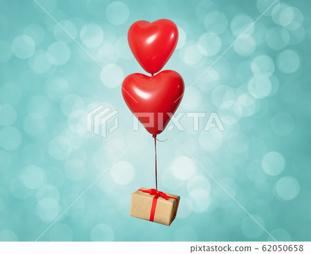 Two heart shaped red air baloon carrying a gift box front of a shiny background. Valentines day and romance concept. Two heart shaped red air baloon carrying a gift box front of a shiny background. Valentines day and romance concept. 62050658