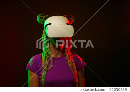 Woman is using virtual reality headset. Neon light studio portrait. 62050819