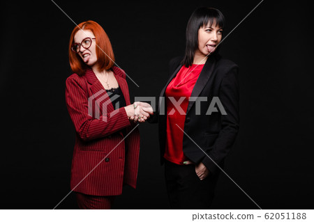 Businesswomen showing disgust while shaking hands Businesswomen showing disgust while shaking hands 62051188