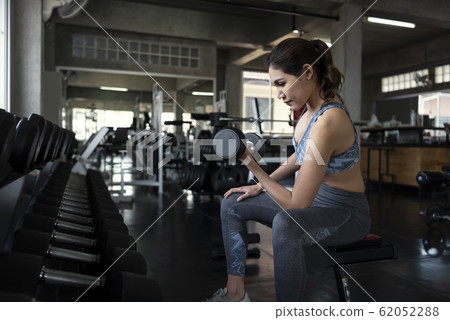 Young asian woman lifting dumbbells in gym 62052288
