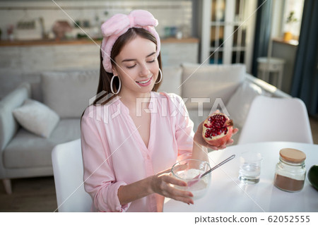 Young pretty girl in a pink headband holding a pomegranate 62052555