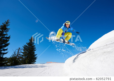 Snowboarder free rider jumping in air downhill on copy space background of blue sky and white snow. 62052791