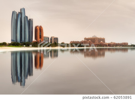 View of Abu Dhabi Skyline on a sunny day with reflection of buildings on water 62053891