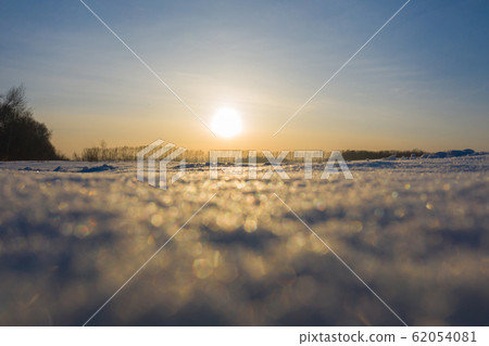 Winter frosty day. The time of sunset. Bokeh snowflakes sparkle in the sun 62054081