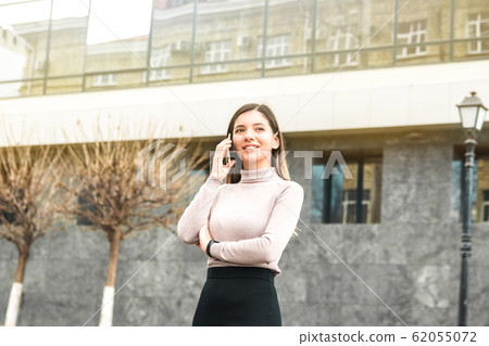 young attractive and confident businesswoman speaking on the phone and smiling in front of business centre 62055072