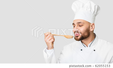 Male Chef Holding Spoon Tasting Dish Standing Over Gray Background, Panorama Male Chef Holding Spoon Tasting Dish Standing Over Gray Background, Panorama 62055153
