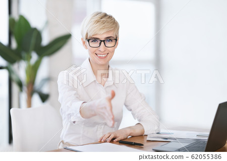 Lady Stretching Hand For Handshake Greeting Sitting At Workplace Lady Stretching Hand For Handshake Greeting Sitting At Workplace 62055386