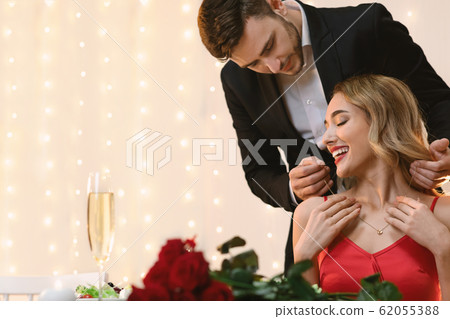Affectionate Man Presenting Golden Necklace To His Girlfriend At Romantic Dinner Affectionate Man Presenting Golden Necklace To His Girlfriend At Romantic Dinner 62055388