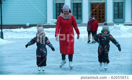 A young woman skating on ice with her children A young woman skating on ice with her children 62055651