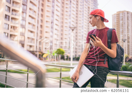 Young man stands with backpack and holds Young man stands with backpack and holds 62056131