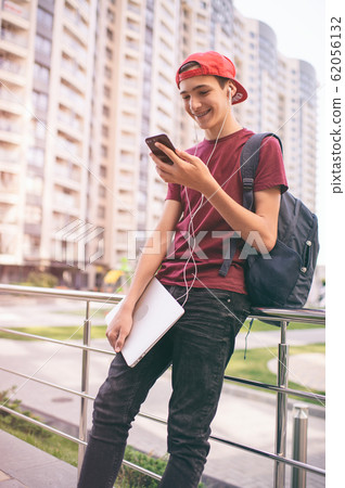 Smiling teenager looks to the cell phone screen, Smiling teenager looks to the cell phone screen, 62056132