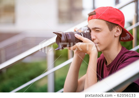 Teenage boy taking photos outdoors. Young man Teenage boy taking photos outdoors. Young man 62056133