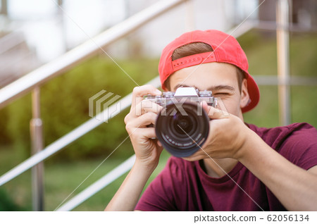 Teenage boy taking photos outdoors. Young man 62056134