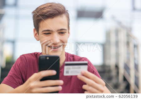Teenage boy with a credit card and mobile phone 62056139