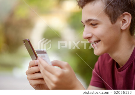 Teenage boy with a credit card and phone makes Teenage boy with a credit card and phone makes 62056153