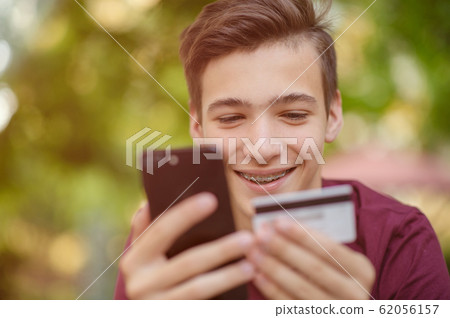 Happy young man is using smartphone and bank card Happy young man is using smartphone and bank card 62056157
