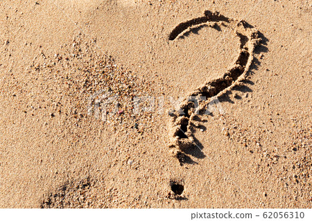 Question mark sign on sand beach near the sea. Question mark sign on sand beach near the sea. 62056310