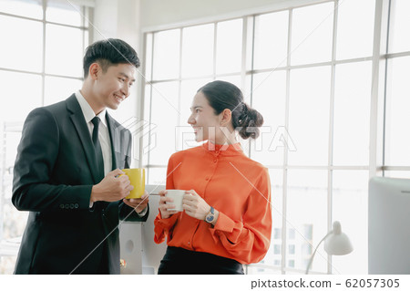 Young couple of professionals chatting during a Young couple of professionals chatting during a 62057305