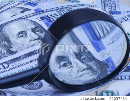 Hundred dollar banknotes under magnifying glass 62057484