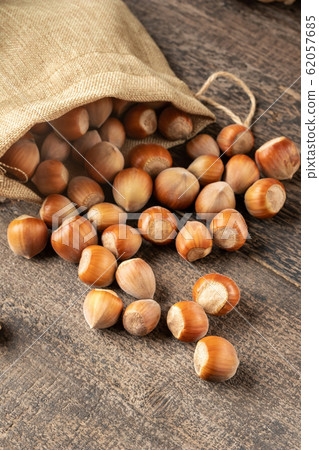 Hazelnuts spilled from a linen bag on a table 62057685