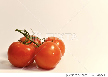 A bunch of fresh red four tomatoes, shot on the side, on a light background, on the left. A bunch of fresh red four tomatoes, shot on the side, on a light background, on the left. 62058271