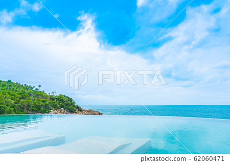 Beautiful outdoor infinity swimming pool in hotel resort with sea ocean view and white cloud blue sky 62060471
