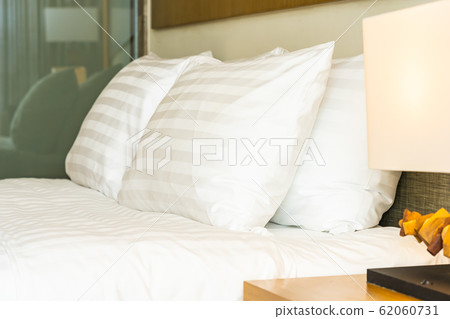 White comfortable pillow on bed decoration with light lamp White comfortable pillow on bed decoration with light lamp 62060731