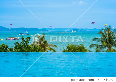 Beautiful outdoor infinity swimming pool with coconut palm tree and sea ocean on blue sky for holiday vacation Beautiful outdoor infinity swimming pool with coconut palm tree and sea ocean on blue sky for holiday vacation 62061089