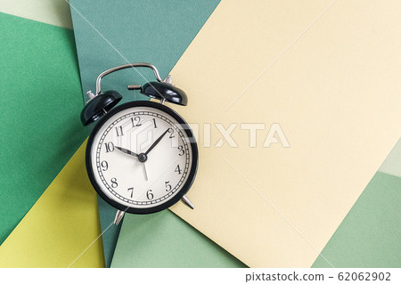 Black alarm clock on geometric green shades paper 62062902