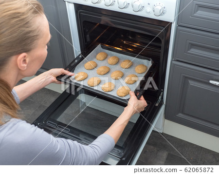 Baking sheet with cookies on the oven.  62065872