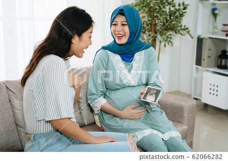 pregnant woman showing ultrasound image to friend pregnant woman showing ultrasound image to friend 62066282