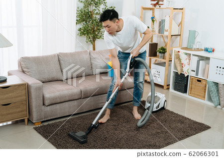 man cleaning carpet with vacuum cleaner man cleaning carpet with vacuum cleaner 62066301