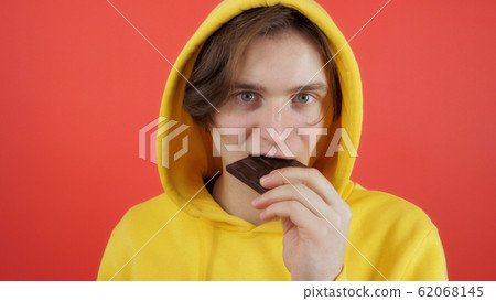 Young man eating sweet chocolate Young man eating sweet chocolate 62068145
