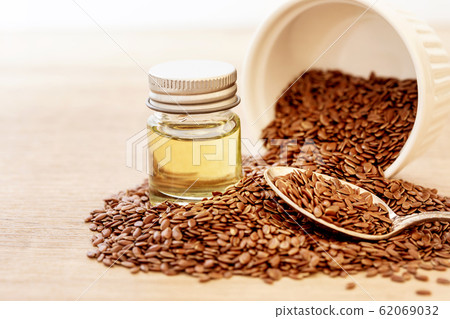 Close up flaxseed essential oil and seeds in wooden spoon , Heart healthy food Close up flaxseed essential oil and seeds in wooden spoon , Heart healthy food 62069032