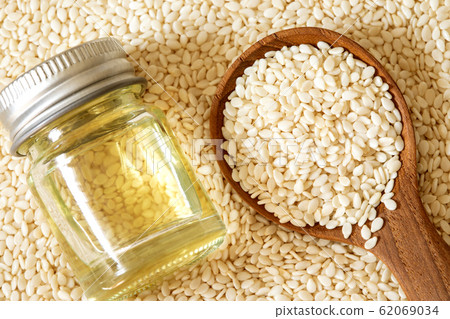 organic  white sesame seeds in wooden spoon with oil bottle 62069034