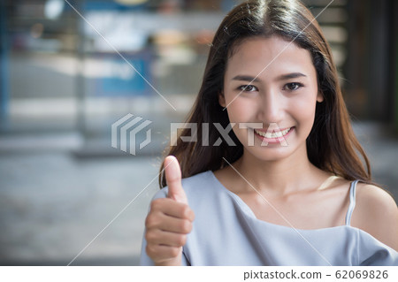 successful girl pointing thumb up; portrait of 62069826