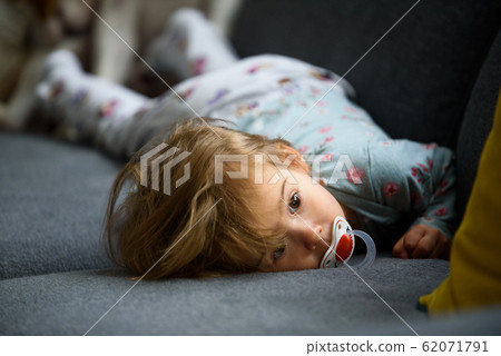 Cute 2 year old Baby girl on a bed on her belly Cute 2 year old Baby girl on a bed on her belly 62071791