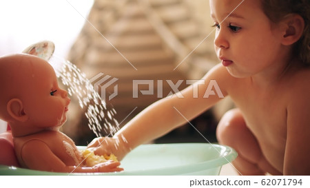 Baby girl washes her doll in the toy bath Baby girl washes her doll in the toy bath 62071794